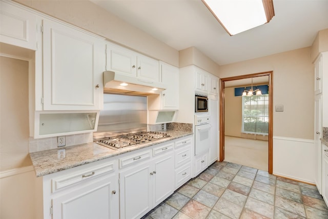 13861 Far Hills Ln, Dallas, TX 75240 - kitchen with gas cooktop, white oven, under cabinet range hood, stainless steel microwave, and white cabinetry
