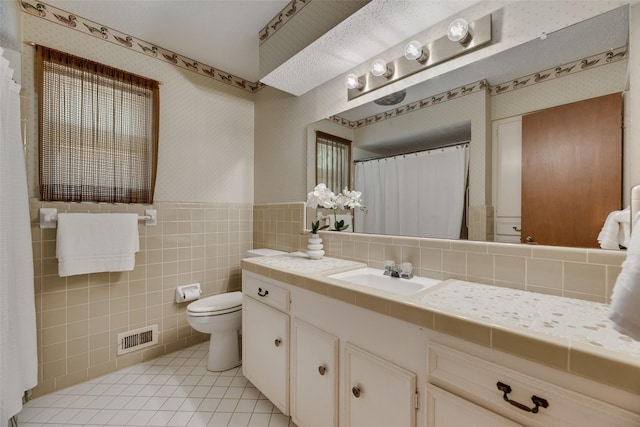 13861 Far Hills Ln, Dallas, TX 75240 - bathroom with vanity, tile patterned floors, wallpapered walls, wainscoting, and tile walls