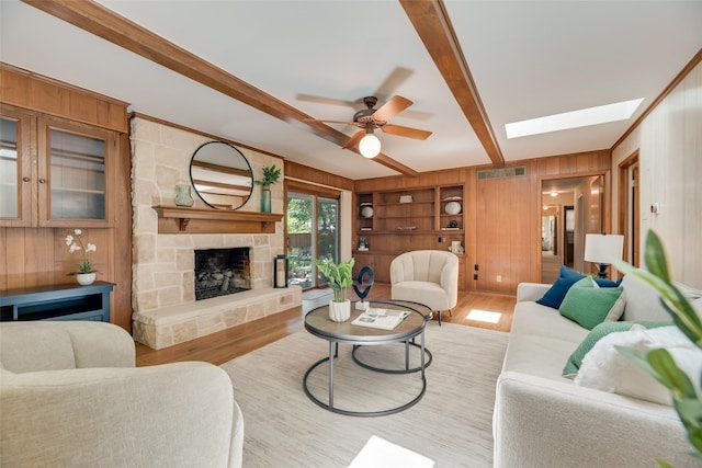 13861 Far Hills Ln, Dallas, TX 75240 - living area featuring wood walls, wood finished floors, beam ceiling, ceiling fan, and a stone fireplace