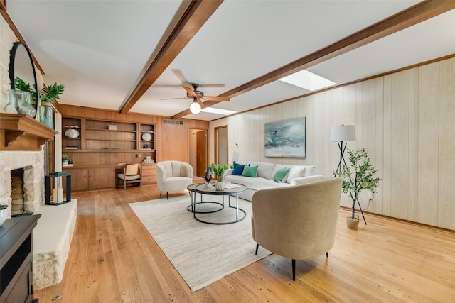 13861 Far Hills Ln, Dallas, TX 75240 - living room with a stone fireplace, beamed ceiling, light wood finished floors, ceiling fan, and wooden walls