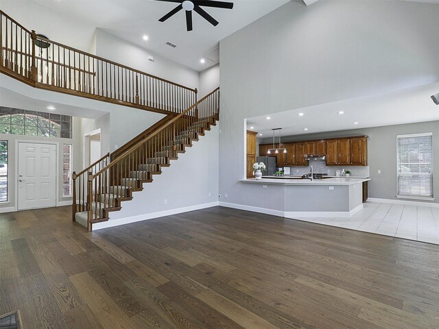 925 Canongate Dr, Flower Mound, TX 75022 - unfurnished living room featuring a towering ceiling, ceiling fan, stairs, wood finished floors, and healthy amount of natural light
