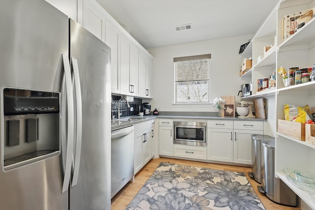 204 Big Sky Cir, Northlake, TX 76226 - kitchen with appliances with stainless steel finishes, white cabinets, light wood finished floors, tasteful backsplash, and light countertops