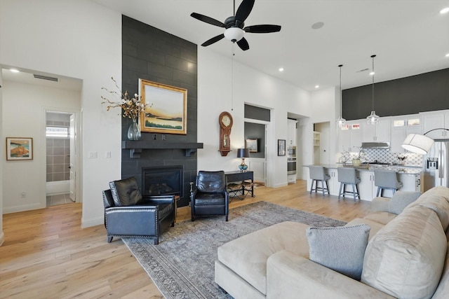 204 Big Sky Cir, Northlake, TX 76226 - living room with a high ceiling, a ceiling fan, light wood-style flooring, a large fireplace, and recessed lighting