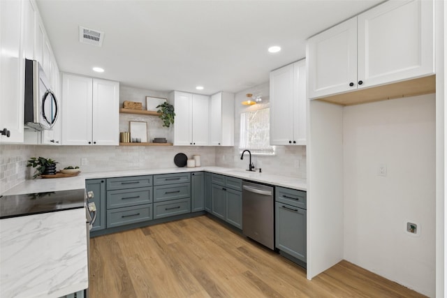 1100 Longworth Dr, Plano, TX 75075 - kitchen with stainless steel appliances, gray cabinetry, white cabinets, open shelves, and light wood finished floors