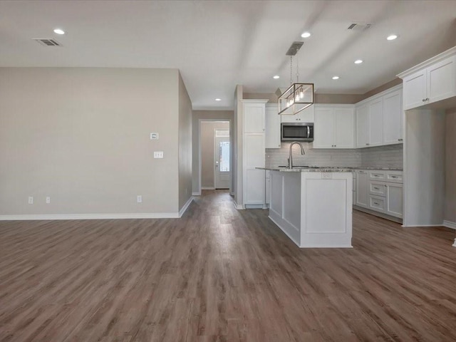 106 Saddle Brook Dr, Lufkin, TX 75904 - kitchen with stainless steel microwave, white cabinets, backsplash, open floor plan, and recessed lighting