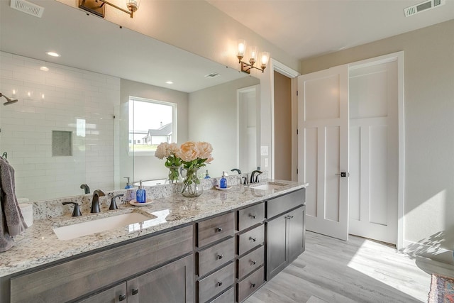 619 Latigo Ct, Weatherford, TX 76088 - bathroom featuring double vanity, wood finished floors, a tile shower, and recessed lighting