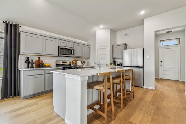 259 Bright Alcove Ct, Lavon, TX 75166 - kitchen with stainless steel appliances, gray cabinets, backsplash, lofted ceiling, and an island with sink