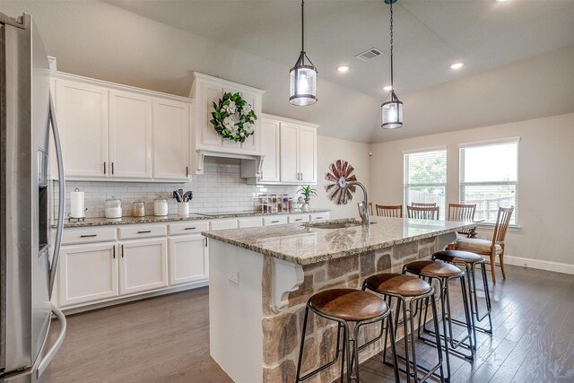 404 Bluffside Trl, Benbrook, TX 76126 - kitchen with stainless steel fridge with ice dispenser, white cabinetry, lofted ceiling, decorative backsplash, and light stone countertops