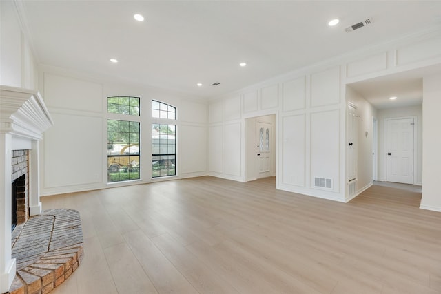 3801 Woodside Dr, Arlington, TX 76016 - unfurnished living room featuring a decorative wall, crown molding, light wood-style floors, a brick fireplace, and recessed lighting