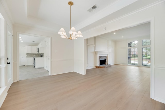 3801 Woodside Dr, Arlington, TX 76016 - unfurnished living room featuring a chandelier, light wood-style floors, a brick fireplace, crown molding, and recessed lighting