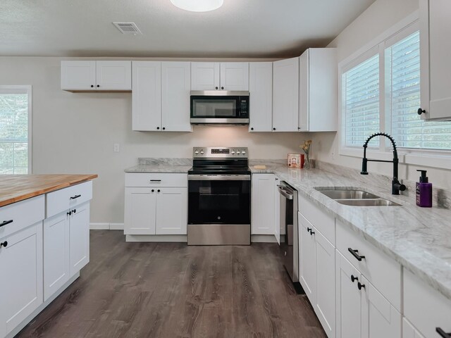1605 N Beaton St, Corsicana, TX 75110 - kitchen featuring stainless steel appliances, dark wood-style flooring, white cabinets, and butcher block countertops