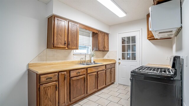 217 Wintercrest Rd, Burleson, TX 76028 - kitchen with black range with gas stovetop, backsplash, light countertops, light tile patterned floors, and brown cabinets