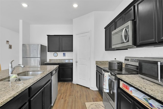 5305 Shady Springs Trl, Fort Worth, TX 76179 - kitchen with appliances with stainless steel finishes, dark cabinetry, light stone countertops, light wood-type flooring, and recessed lighting