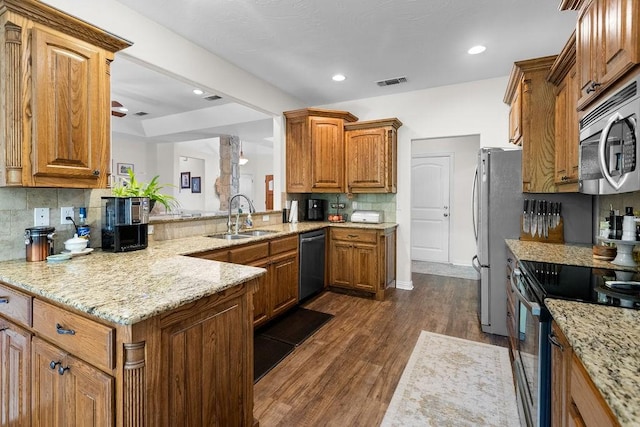 2110 Park Rdg, Denison, TX 75020 - kitchen with stainless steel appliances, backsplash, brown cabinetry, dark wood finished floors, and light stone counters