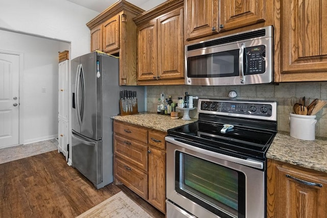 2110 Park Rdg, Denison, TX 75020 - kitchen featuring stainless steel appliances, decorative backsplash, brown cabinets, and light stone countertops