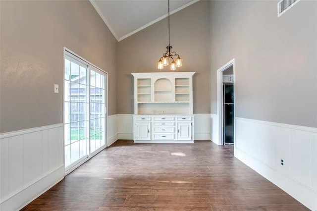 403 Gingerbread Ln, Waxahachie, TX 75165 - unfurnished dining area featuring crown molding, high vaulted ceiling, a chandelier, a wainscoted wall, and dark wood-type flooring