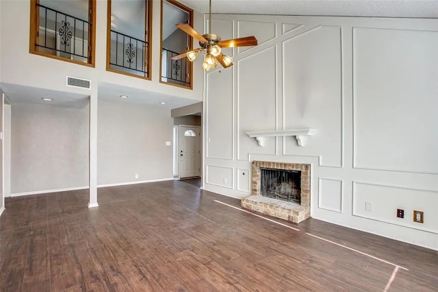 403 Gingerbread Ln, Waxahachie, TX 75165 - unfurnished living room with a decorative wall, ceiling fan, a fireplace, and dark wood-style flooring
