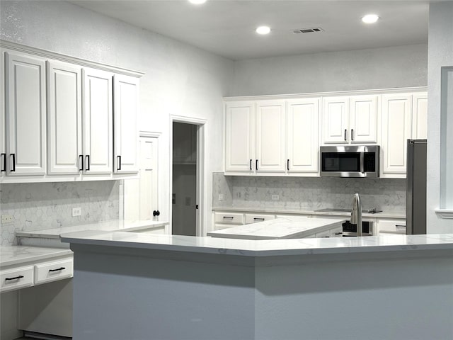 4201 Iron Ln, Mansfield, TX 76063 - kitchen featuring stainless steel microwave, decorative backsplash, white cabinets, light stone counters, and recessed lighting