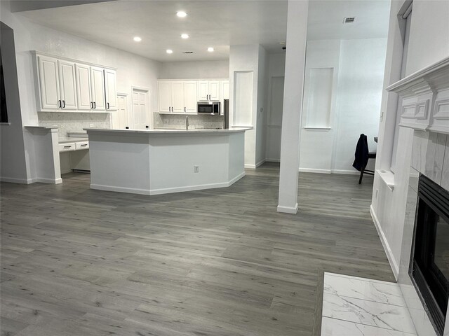 4201 Iron Ln, Mansfield, TX 76063 - kitchen with stainless steel microwave, a fireplace, recessed lighting, white cabinetry, and a kitchen island with sink