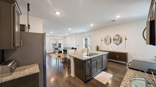 2026 Ocelot St, Crandall, TX 75114 - kitchen with stainless steel appliances, dark brown cabinetry, dark wood finished floors, a center island with sink, and light stone counters