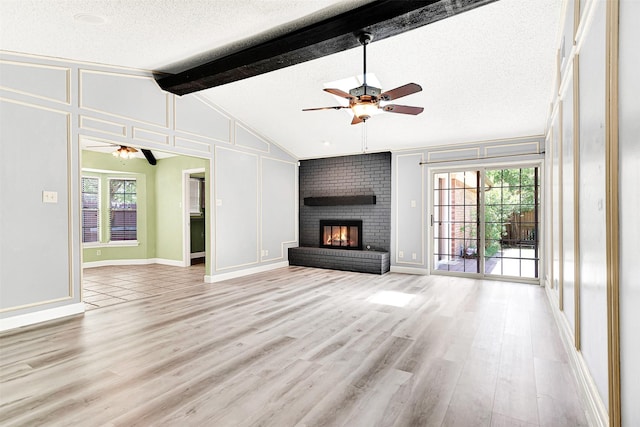 4005 Azalea Ln, Garland, TX 75043 - unfurnished living room featuring ceiling fan, a decorative wall, light wood-style floors, a textured ceiling, and a fireplace