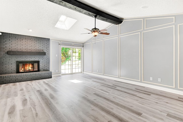 4005 Azalea Ln, Garland, TX 75043 - unfurnished living room featuring a decorative wall, a textured ceiling, wood finished floors, a skylight, and a ceiling fan