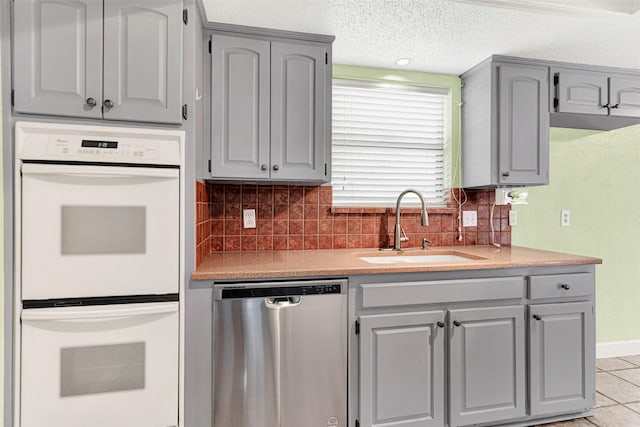 4005 Azalea Ln, Garland, TX 75043 - kitchen with stainless steel dishwasher, double oven, backsplash, gray cabinets, and a textured ceiling