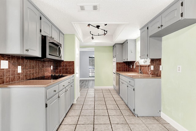 4005 Azalea Ln, Garland, TX 75043 - kitchen with black electric stovetop, stainless steel microwave, a raised ceiling, light tile patterned flooring, and light countertops