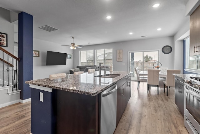 1154 Holcombe Dr, Anna, TX 75409 - kitchen featuring stainless steel appliances, light wood finished floors, a kitchen island with sink, stone counters, and a ceiling fan