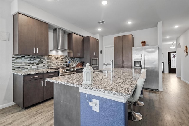 1154 Holcombe Dr, Anna, TX 75409 - kitchen with stainless steel appliances, wall chimney exhaust hood, light wood-type flooring, dark brown cabinets, and recessed lighting