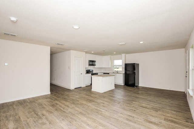 2719 William St, Mabank, TX 75147 - kitchen featuring black appliances, open floor plan, a center island, wood finished floors, and white cabinetry
