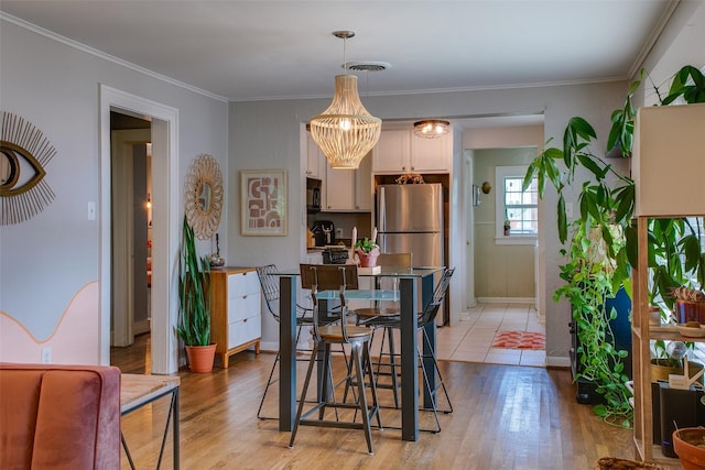 1211 Lansford Ave, Dallas, TX 75224 - dining space with light wood-style flooring, a chandelier, and ornamental molding