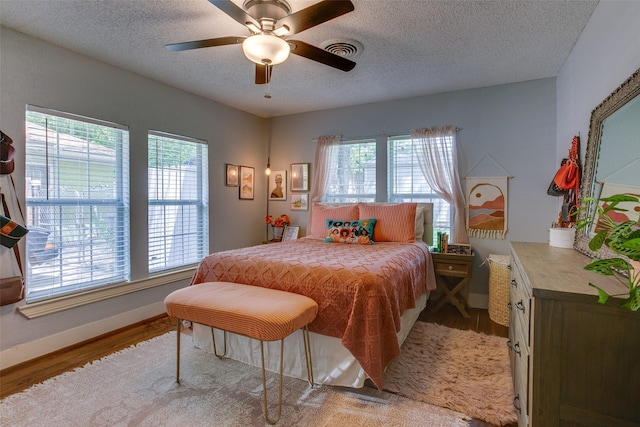 1211 Lansford Ave, Dallas, TX 75224 - bedroom with wood finished floors, a textured ceiling, and a ceiling fan