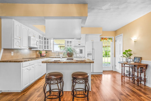 1748 Old Southmayd Rd, Sherman, TX 75092 - kitchen with white appliances, light wood finished floors, a center island, white cabinetry, and a breakfast bar area