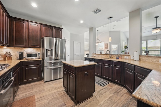 1000 Barn Owl Dr, Little Elm, TX 75068 - kitchen with stainless steel appliances, light wood-style flooring, light stone countertops, dark brown cabinets, and recessed lighting
