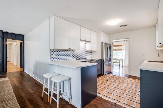 2528 Royal Ln, Denton, TX 76209 - kitchen featuring stainless steel appliances, a breakfast bar, wood finished floors, and white cabinets