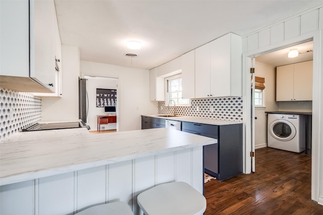 2528 Royal Ln, Denton, TX 76209 - kitchen with washer / dryer, dark wood finished floors, a peninsula, tasteful backsplash, and plenty of natural light