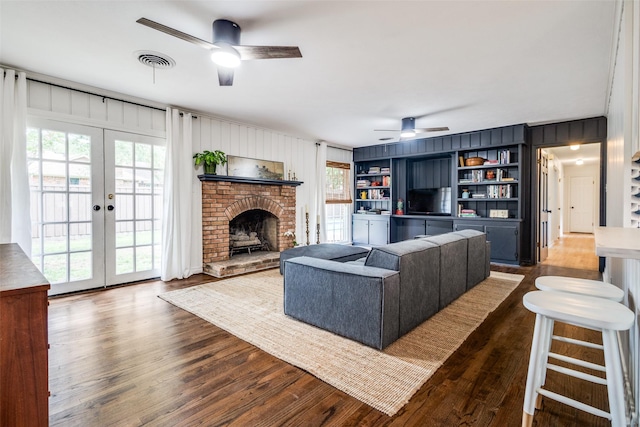 2528 Royal Ln, Denton, TX 76209 - living room featuring a ceiling fan, dark wood-style floors, a brick fireplace, french doors, and wooden walls