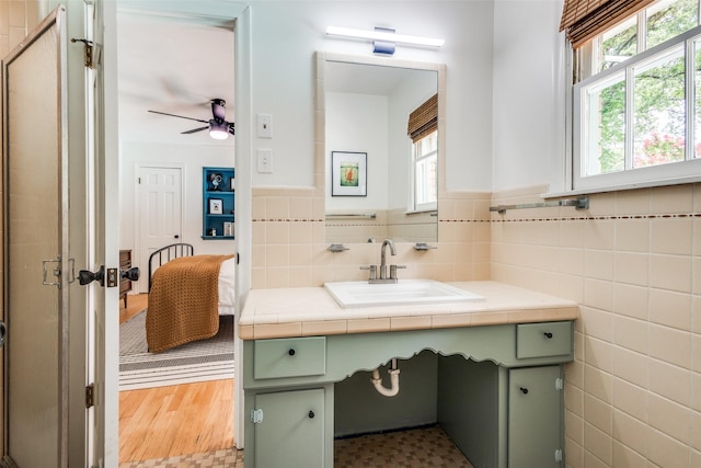 2528 Royal Ln, Denton, TX 76209 - bathroom featuring tile walls, vanity, healthy amount of natural light, a ceiling fan, and wainscoting