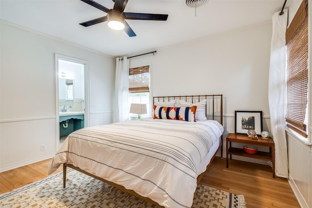 2528 Royal Ln, Denton, TX 76209 - bedroom featuring wood finished floors, crown molding, a wainscoted wall, ensuite bathroom, and a ceiling fan