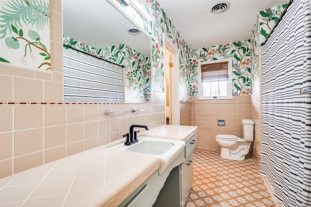 2528 Royal Ln, Denton, TX 76209 - bathroom with tile walls, wallpapered walls, vanity, and a wainscoted wall