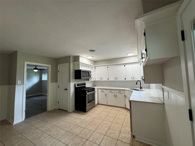 2410 W Collin St, Corsicana, TX 75110 - kitchen featuring stainless steel appliances, light countertops, wainscoting, light tile patterned floors, and ceiling fan