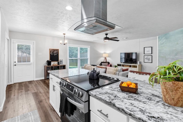 7116 Chapman Dr, North Richland Hills, TX 76182 - kitchen with stainless steel range with electric cooktop, a textured ceiling, island exhaust hood, wood finished floors, and healthy amount of natural light