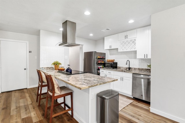 7116 Chapman Dr, North Richland Hills, TX 76182 - kitchen with stainless steel appliances, island range hood, light wood-type flooring, a kitchen bar, and light stone counters