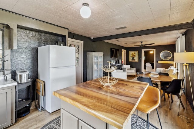 601 E San Saba St, Wortham, TX 76693 - kitchen with freestanding refrigerator, a ceiling fan, light wood finished floors, and light countertops