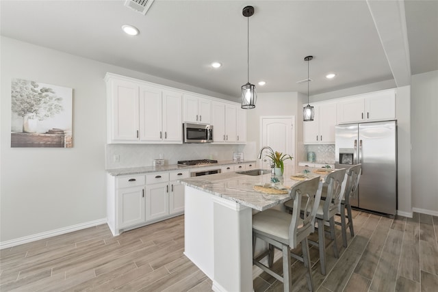 1420 Whitetail Ln, Azle, TX 76020 - kitchen featuring stainless steel appliances, light wood finished floors, a kitchen bar, backsplash, and white cabinetry