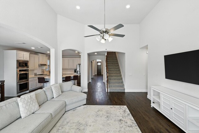 4336 Westminster Ave, Celina, TX 76227 - living area with arched walkways, ceiling fan, stairs, dark wood finished floors, and high vaulted ceiling