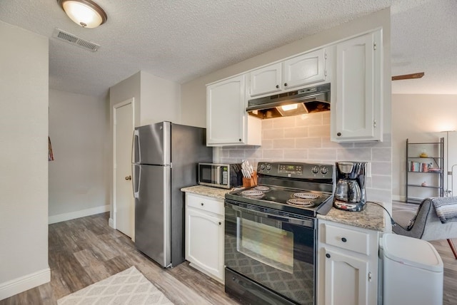1833 Alonsdale Dr, Garland, TX 75040 - kitchen with stainless steel appliances, under cabinet range hood, a textured ceiling, white cabinetry, and light wood-type flooring