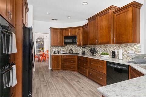 1918 Palace Dr, Grand Prairie, TX 75050 - kitchen featuring black appliances, light wood finished floors, tasteful backsplash, brown cabinets, and recessed lighting