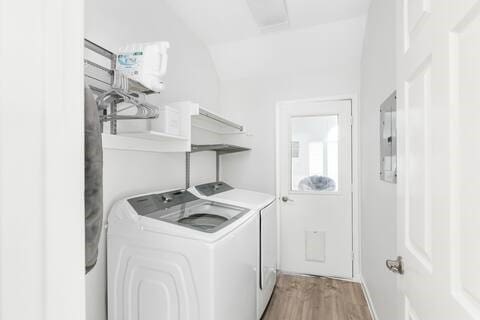 1918 Palace Dr, Grand Prairie, TX 75050 - laundry area with washing machine and clothes dryer, light wood finished floors, and electric panel